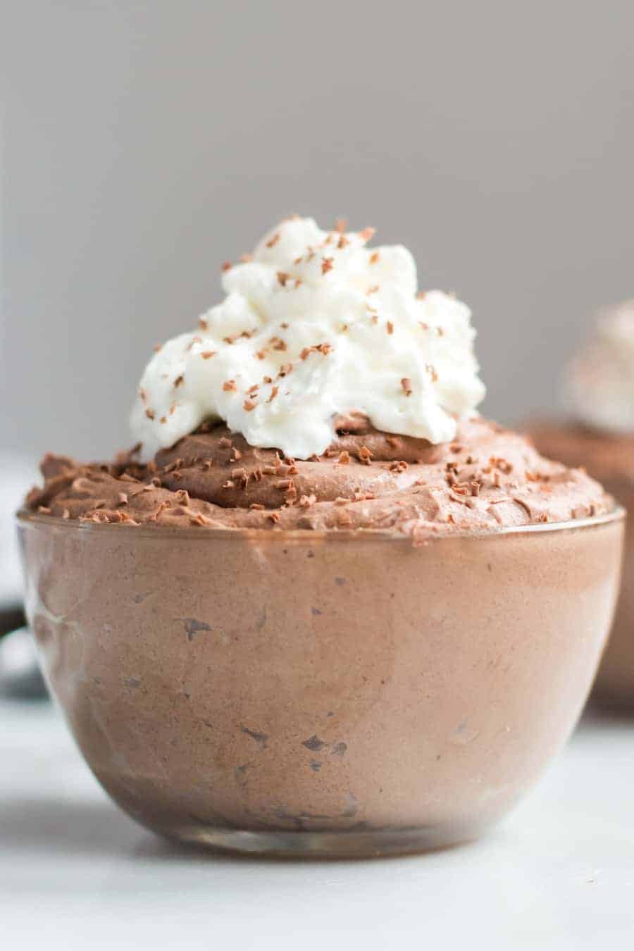 Small glass bowl filled with chocolate mousse and topped with whipped cream and chocolate shavings.