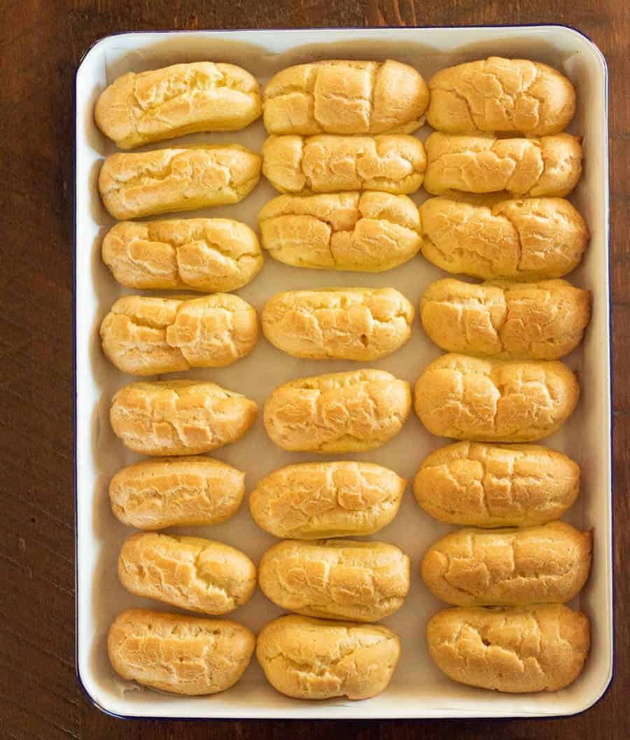 Baked eclairs in a white pain before they are filled with custard or iced. 