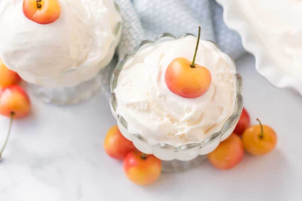 whipped cream in a parfait dish with cherries on top