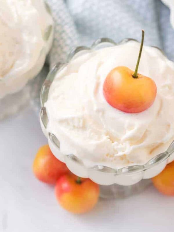 whipped cream in a parfait dish with cherries on top