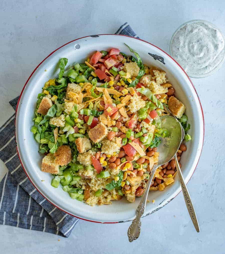 Mixed together cornbread salad with serving spoons