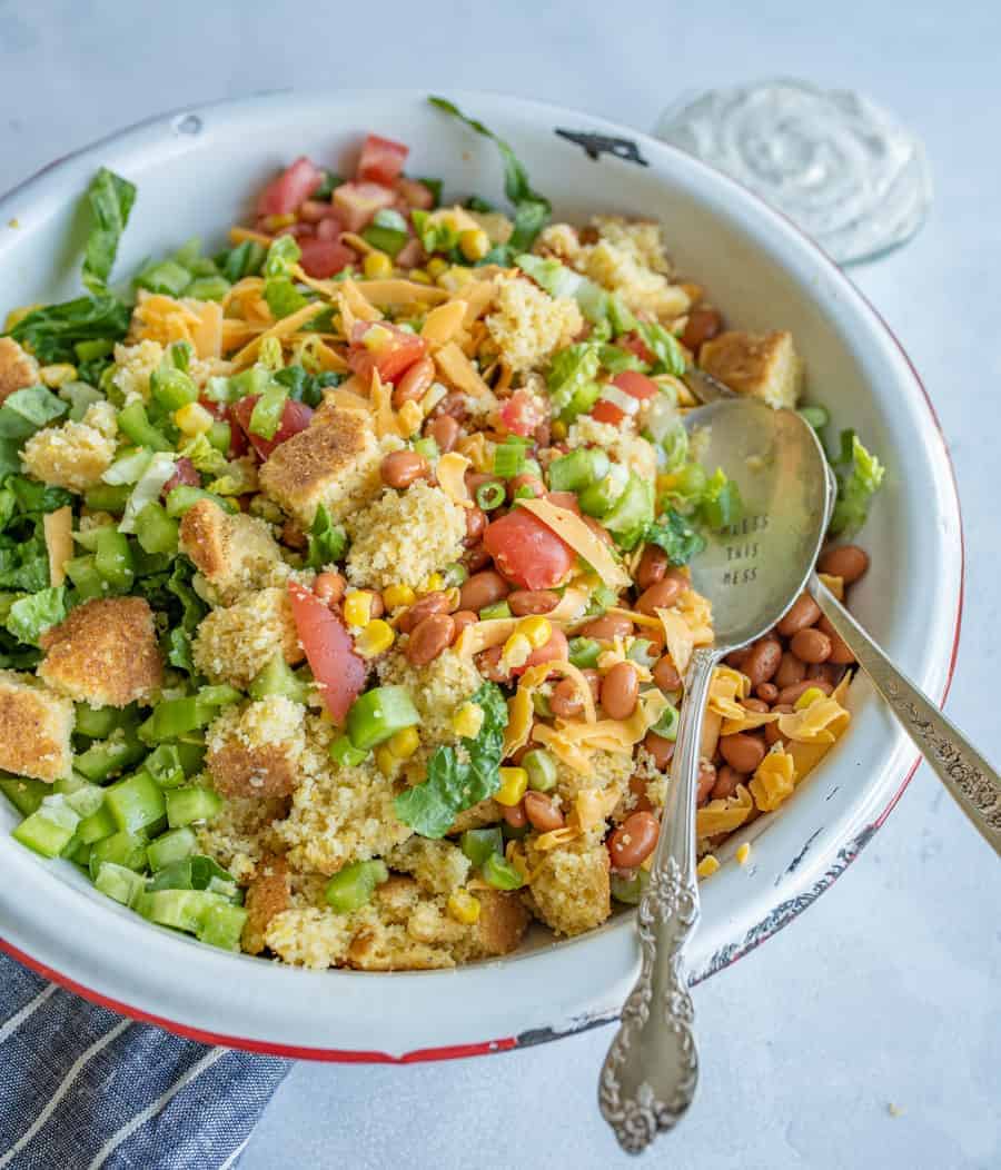 cornbread salad recipe mixed together in a white bowl.