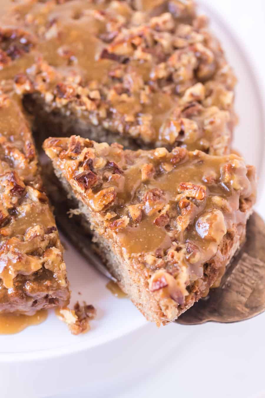 broiled nut icing on old fashioned oatmeal cake with slice being removed on spatula