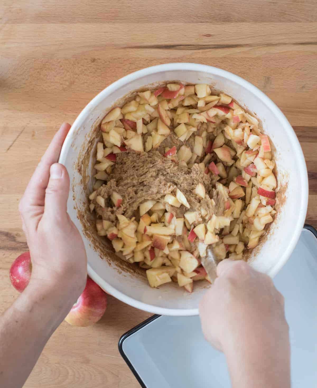 A mixing bowl with cake batter and chopped apples