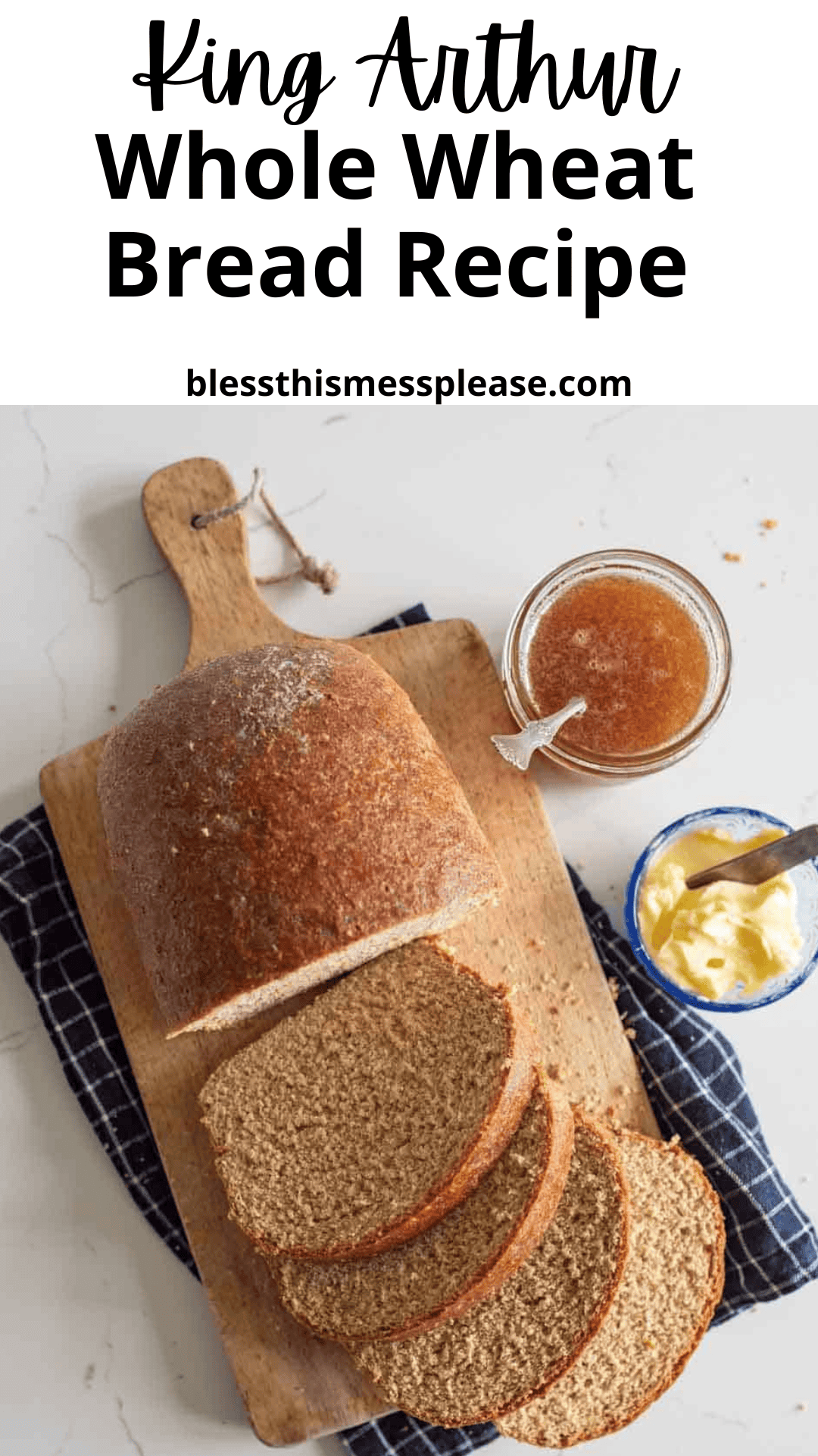A loaf of whole wheat bread, partially sliced on a wooden cutting board with a jar of jam and butter, viewed from above. Text reads: “King Arthur Whole Wheat Bread Recipe” and “blessthismessplease.com”—the perfect whole wheat bread recipe!.