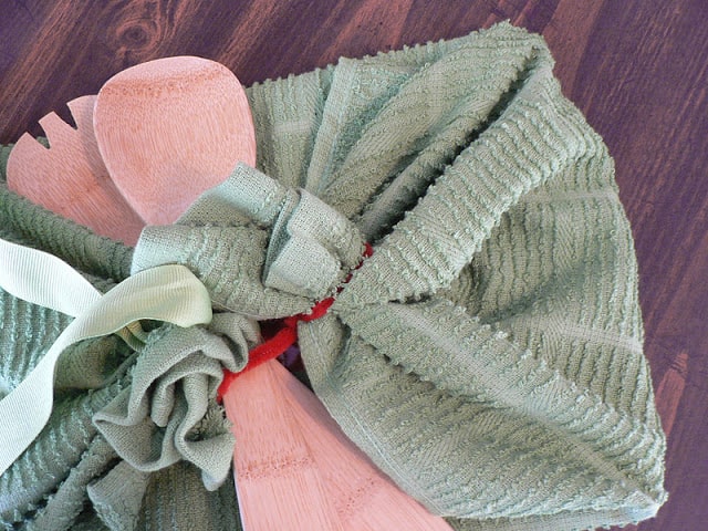 An image showing the process for wrapping a rectangular gift in a green tea towel