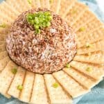 beef and onion cheese ball surrounded by crackers on a white plate