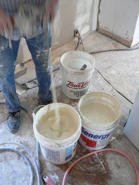 A contractor mixing white sheetrock mud in buckets