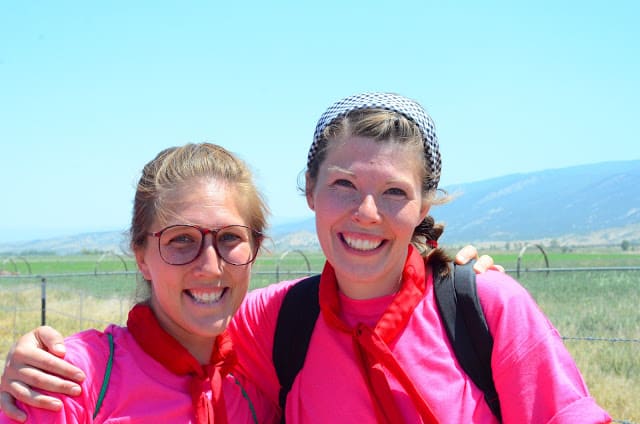 Image of two women outdoors, smiling with an arm around each other and both wearing magenta tops