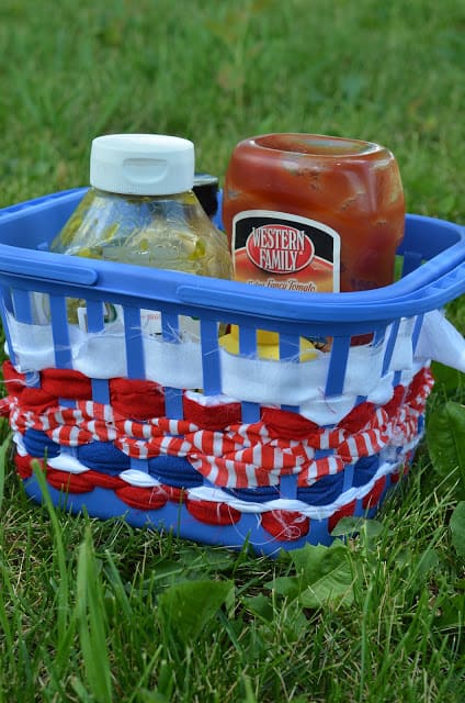 A blue plastic basket for condiments decorated with red, white and blue ribbons