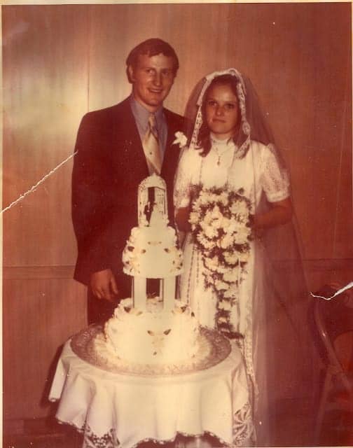 An old wedding photo of a couple with their wedding cake