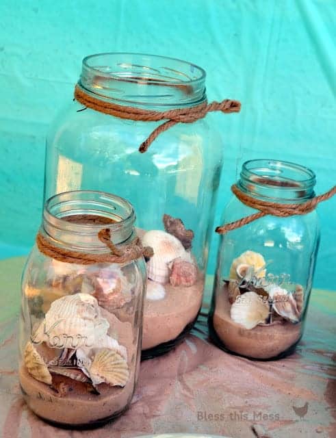3 mason jars with sand and seashells and a rope at the top