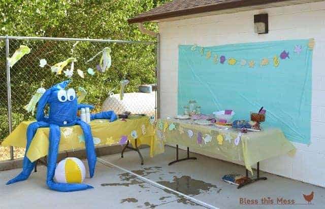 Two party tables with a giant inflatable octopus and beach-themed decorations