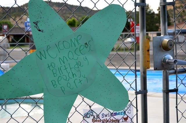 A green paper star-shaped welcome sign in children's handwriting hanging on a fence