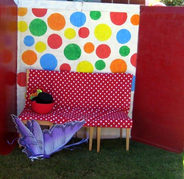 A circus-themed outdoor photo booth with polka-dot background, bench and props