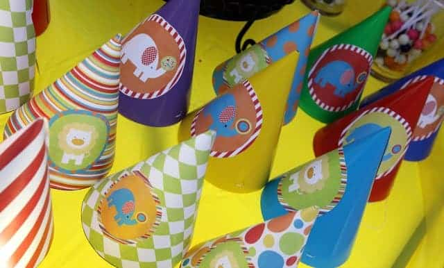 Party hats with cartoon circus animals on a yellow table