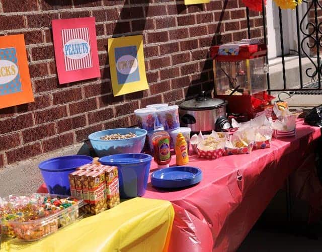 A buffet table filled with circus-themed foods and snacks, including Cracker Jack, peanuts and candy