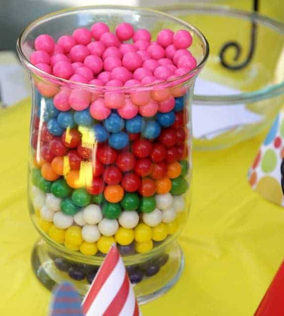 A clear glass vase filled with layers of different colored candies