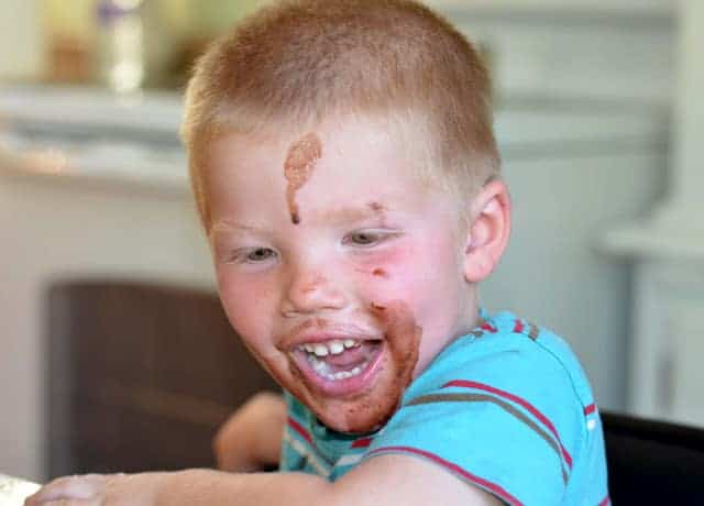 Image of a smiling little boy with chocolate pop drips on his face