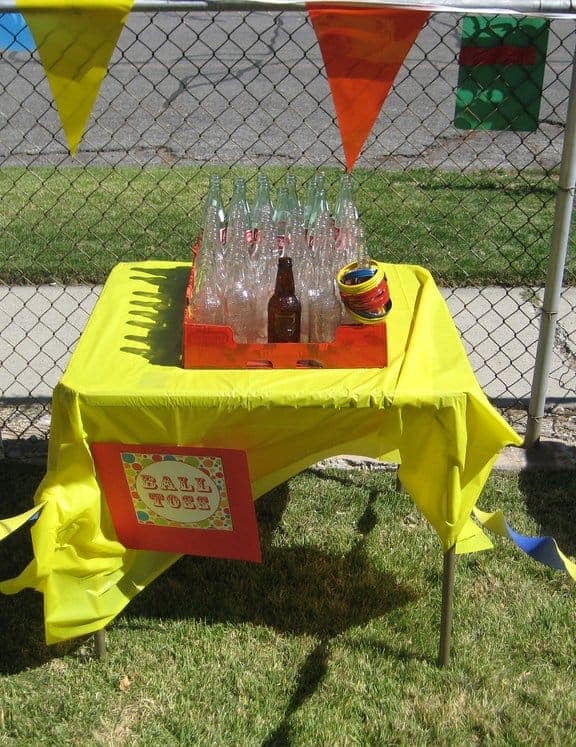 Clear glass bottles on a table with yellow tablecloth for Bottle Toss game