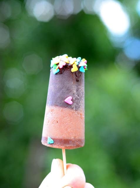 A homemade fudge pop with two shades of chocolate topped with heart-shaped sprinkles