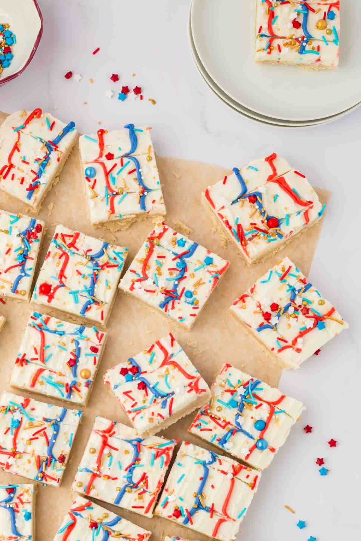 top view of red white and blue iced sugar cookie bars with star shaped sprinkles on wax paper