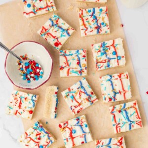 top view of red white and blue iced sugar cookie bars with star shaped sprinkles on wax paper