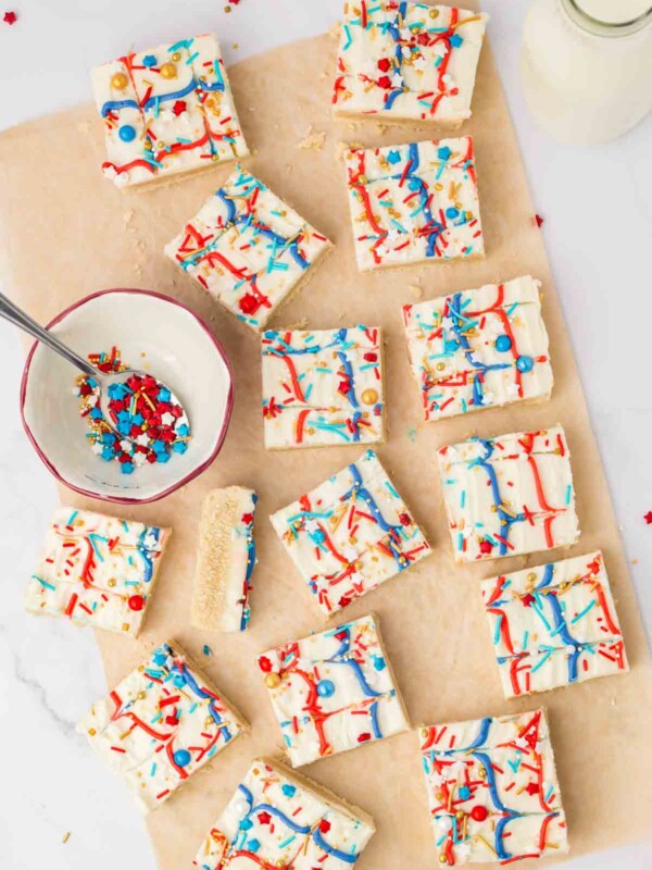 top view of red white and blue iced sugar cookie bars with star shaped sprinkles on wax paper