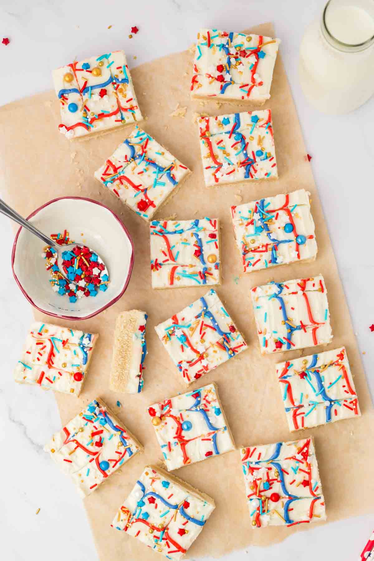 top view of red white and blue iced sugar cookie bars with star shaped sprinkles on wax paper