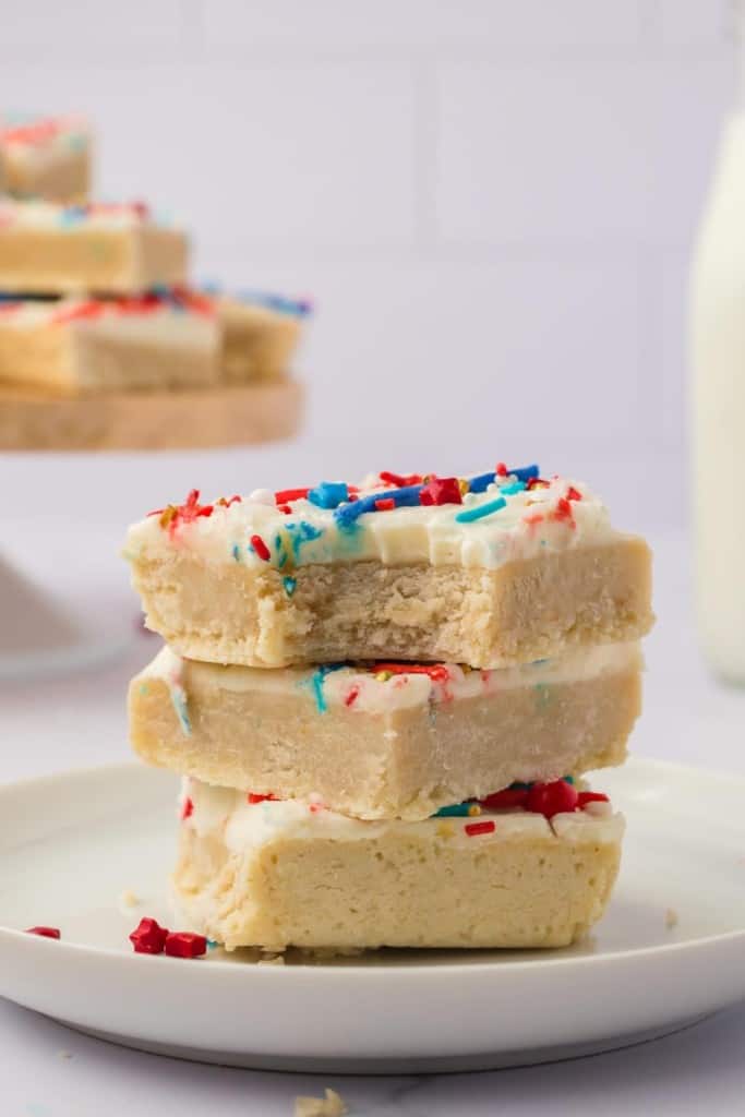 stack of red white and blue iced sugar cookie bars with the top one having a bite taken out
