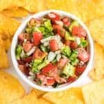 chunky fresh salsa in a white dish with tortilla chips all around