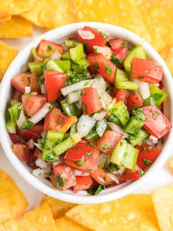 chunky fresh salsa in a white dish with tortilla chips all around