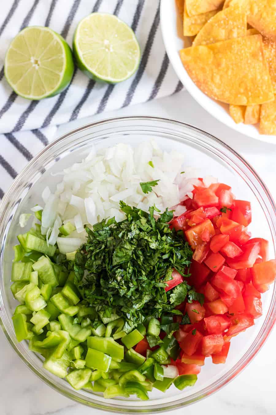 chunky fresh salsa ingredients in a clear glass mixing bowl