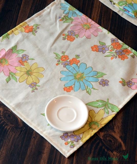 A colorful floral-printed cloth napkin on a table with a white saucer on it