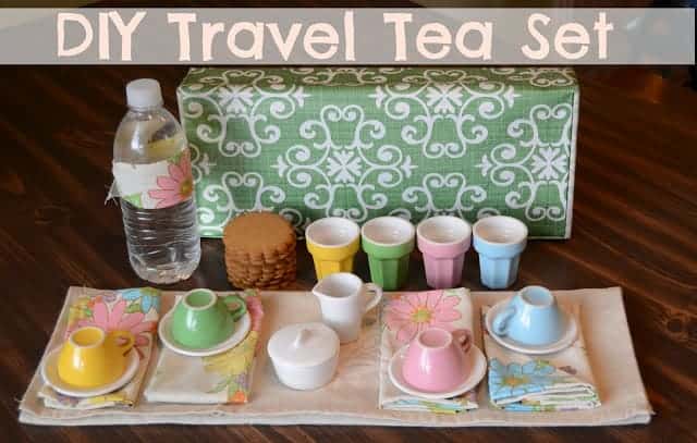 Title image for DIY Travel Tea Set  and a set of colorful tea cups and saucers on floral napkins and a stack of cookies