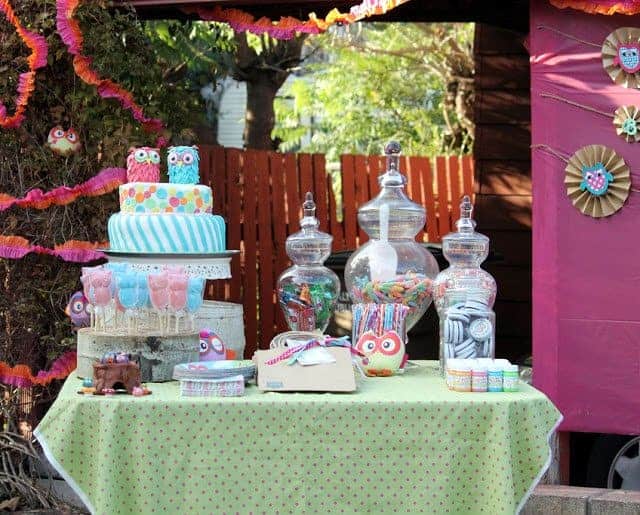 A table with owl-themed birthday decorations and treats