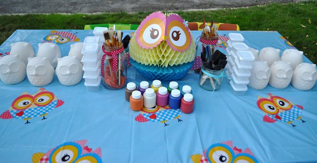 A table with painting supplies and ceramic owls for painting