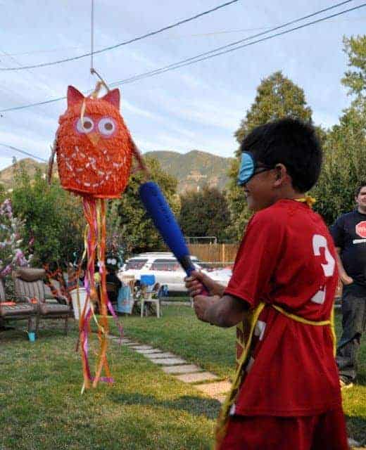 A child striking an owl pinata with a bat