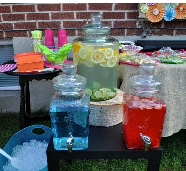 A display of colorful drinks in glass dispensers, cups, and ice