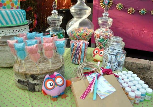 A table with owl-themed candy and party favors