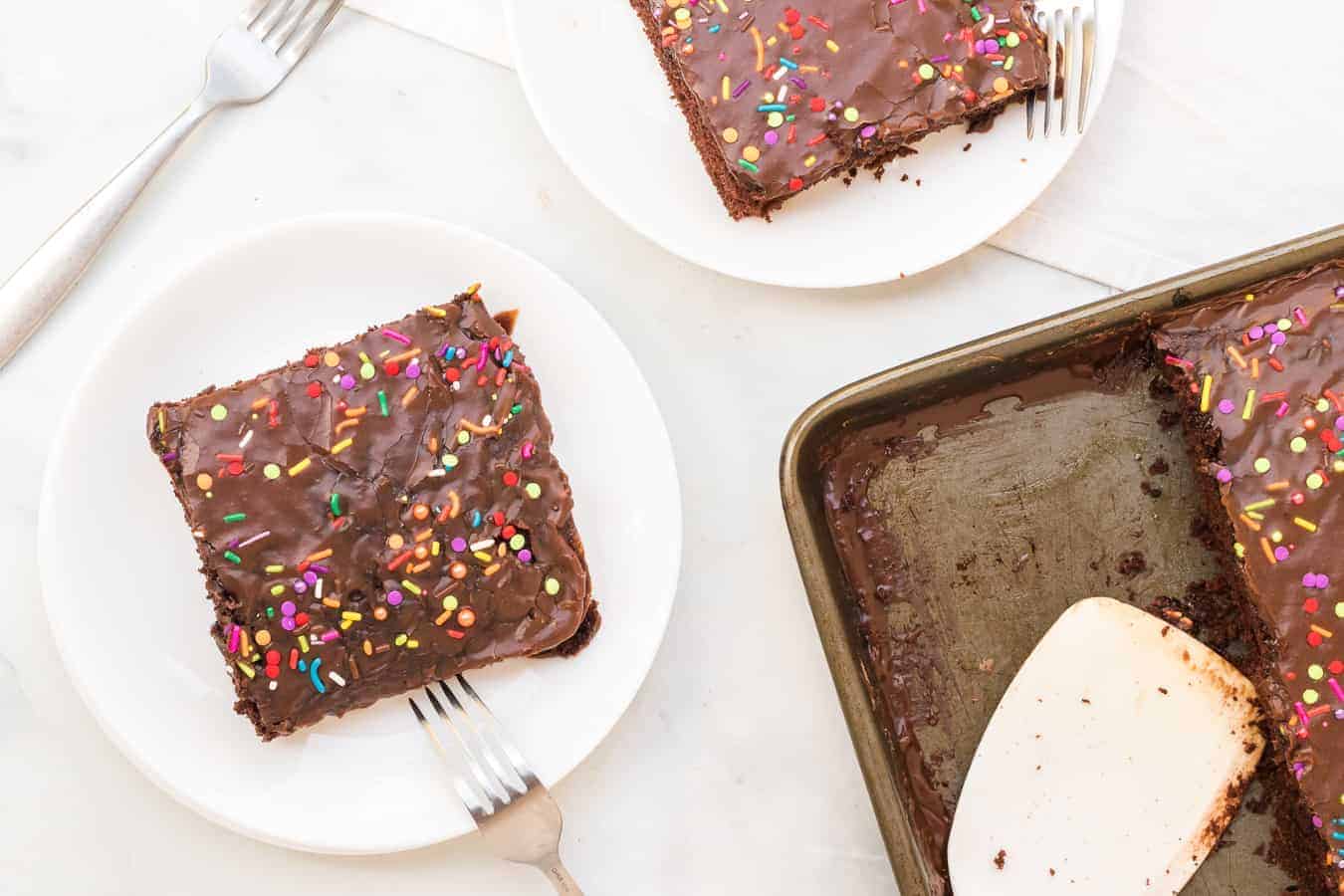 This chocolate sheet cake recipe with easy-to-make homemade icing is the tastiest dessert ever! If you're celebrating a birthday any time soon, this cake is a perfect option. You can easily make a birthday cake (or any celebration cake) with this semi-homemade recipe that is seriously divine! #sheetcake #chocolatesheetcake #homemadecake #cake #chocolatecake #cakerecipe #sheetcakerecipe #easycakerecipe #homemadeicing #chocolateicing