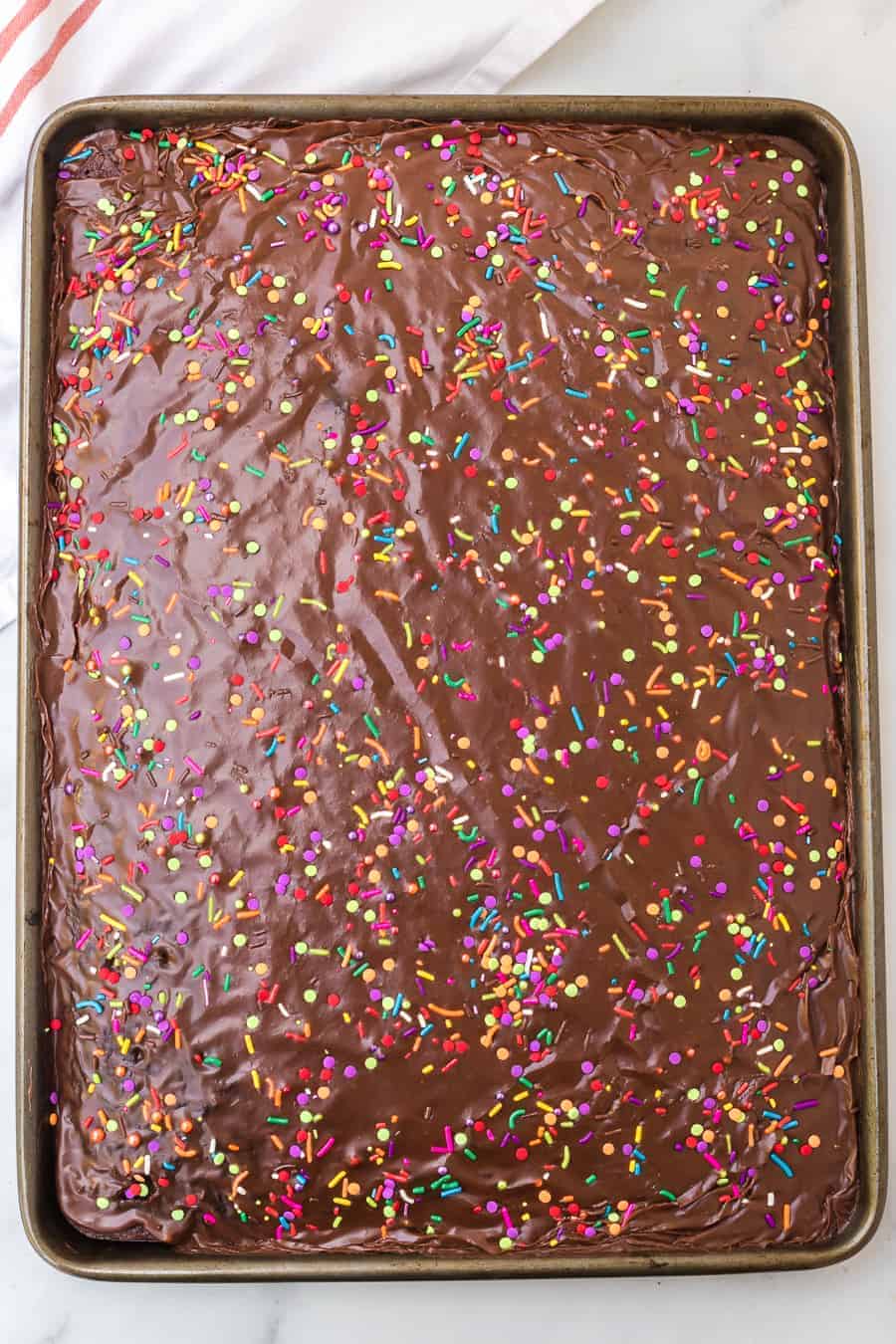 chocolate sheet cake with colored sprinkles in metal rectangle pan.