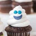 a chocolate cupcake with white frosting piped to a ghost shape with a smiley face