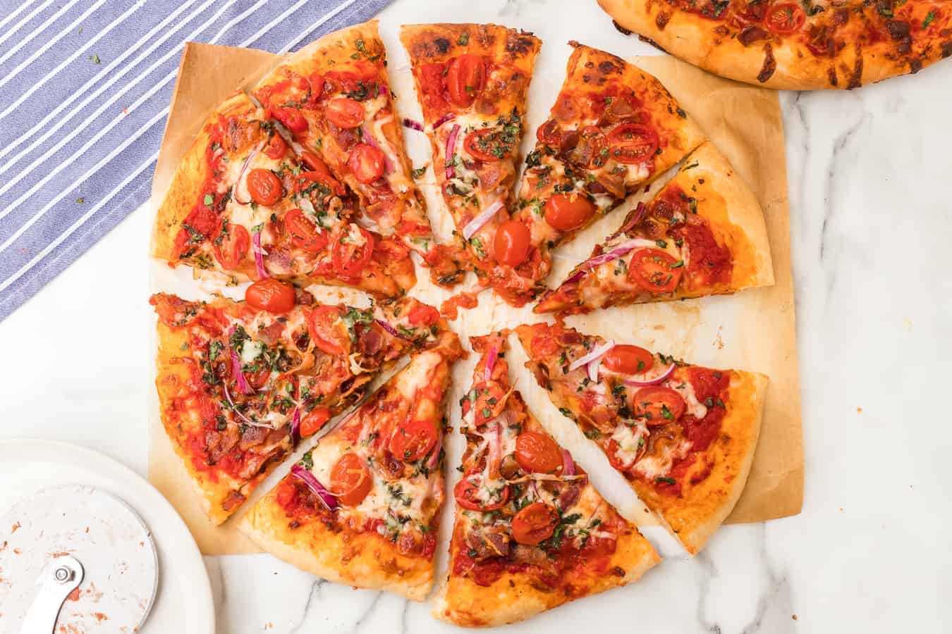 Homemade pizza dough topped with bacon, cheese, tomatoes, and herbs is the perfect pizza to make tonight. Your whole family will love it! #pizza #homemadepizza #tomatobaconpizza