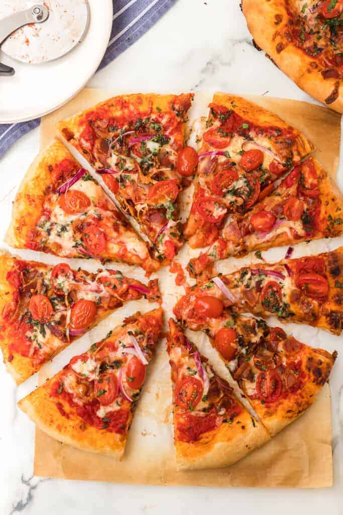 a whole herbed tomato and bacon pizza on parchment