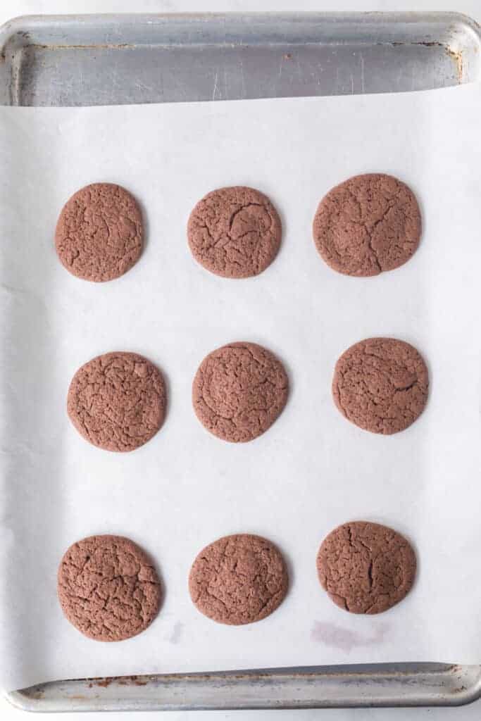 the top of homemade oreos on parchment on a baking sheet, baked
