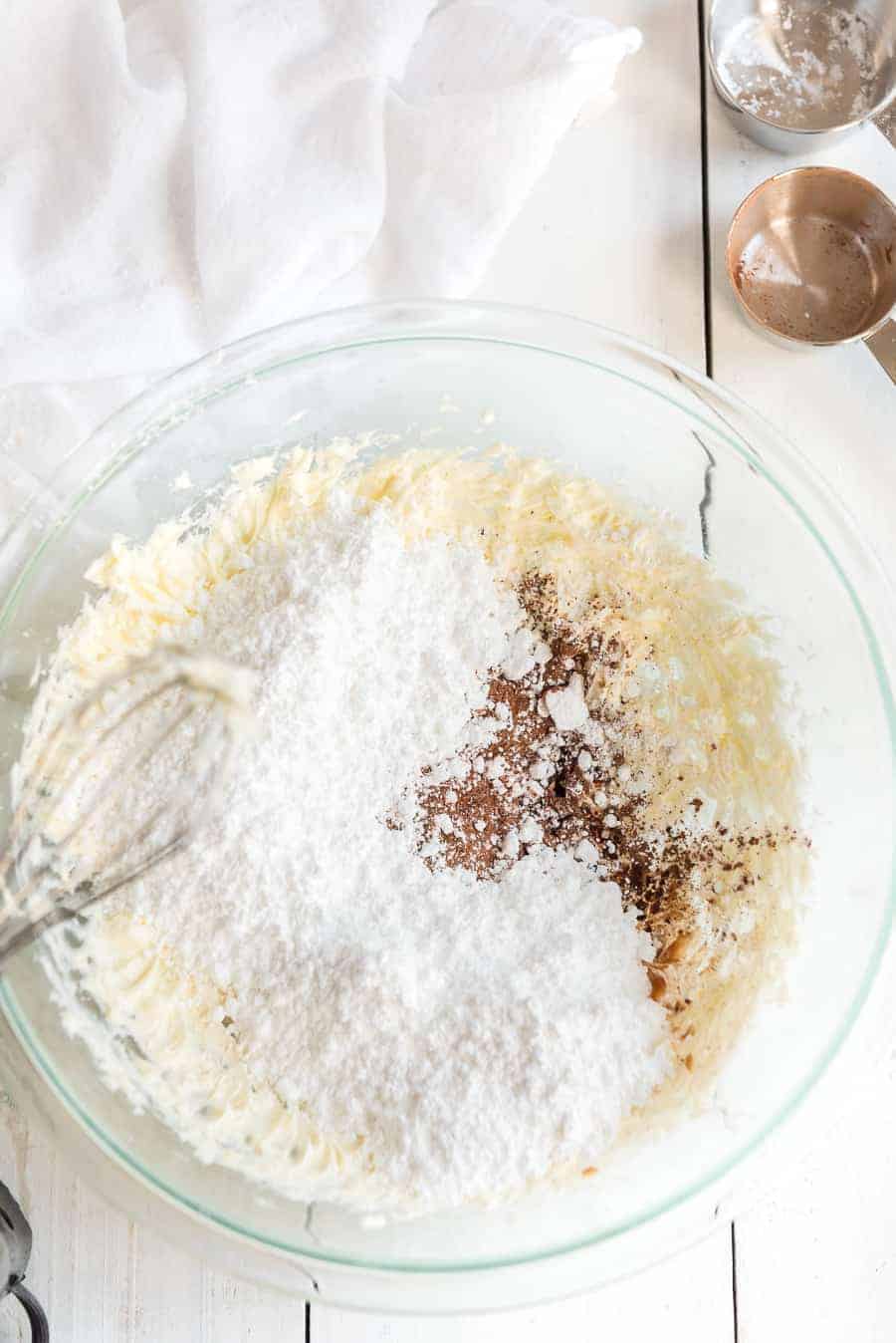 butter, sugar, and coco powder in a glass mixing bowl with a whisk.