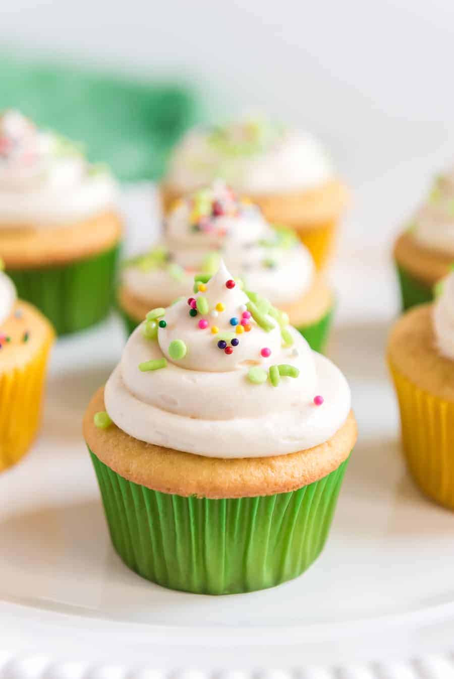 Up close shot of a cupcake that has been iced with vanilla frosting and a variety of sprinkles.
