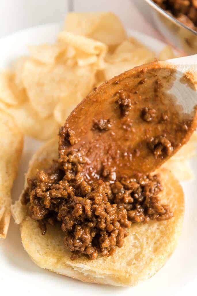 spoon putting sloppy joe meat on a bun