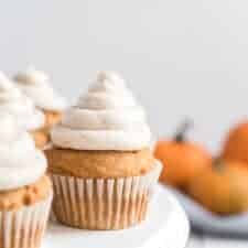 light golden pumpkin cupcakes with a cream colored and cinnamon speckled icing